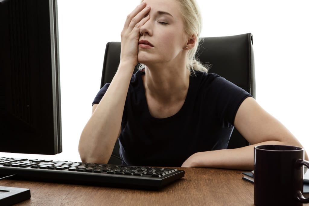 woman sitting at her desk with her head in her hands stressed out