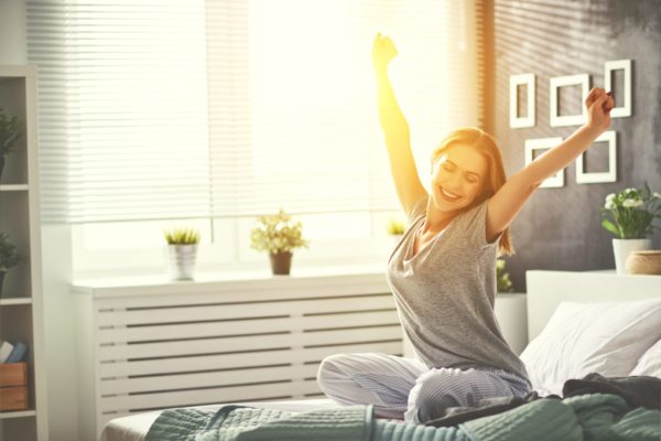 young woman woke up in the morning in the bedroom by the window with her back Brilliant Balance Basics, How To Get More Energy: 21 Day Energy Challenge